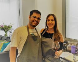 זוג עם סינרים אפורים בסדנת בישול זוגית